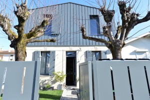 Façade sud de la maison des charmilles. Surélévation en bardage métallique gris moyen, et rez-de-chaussée réhabilité: pierre et bois. / © Justine Reverchon Architecte
