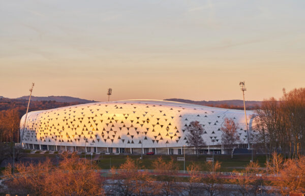 Vue du volume du stade à la tombée de la nuit / Atelier Ferret Architectures
