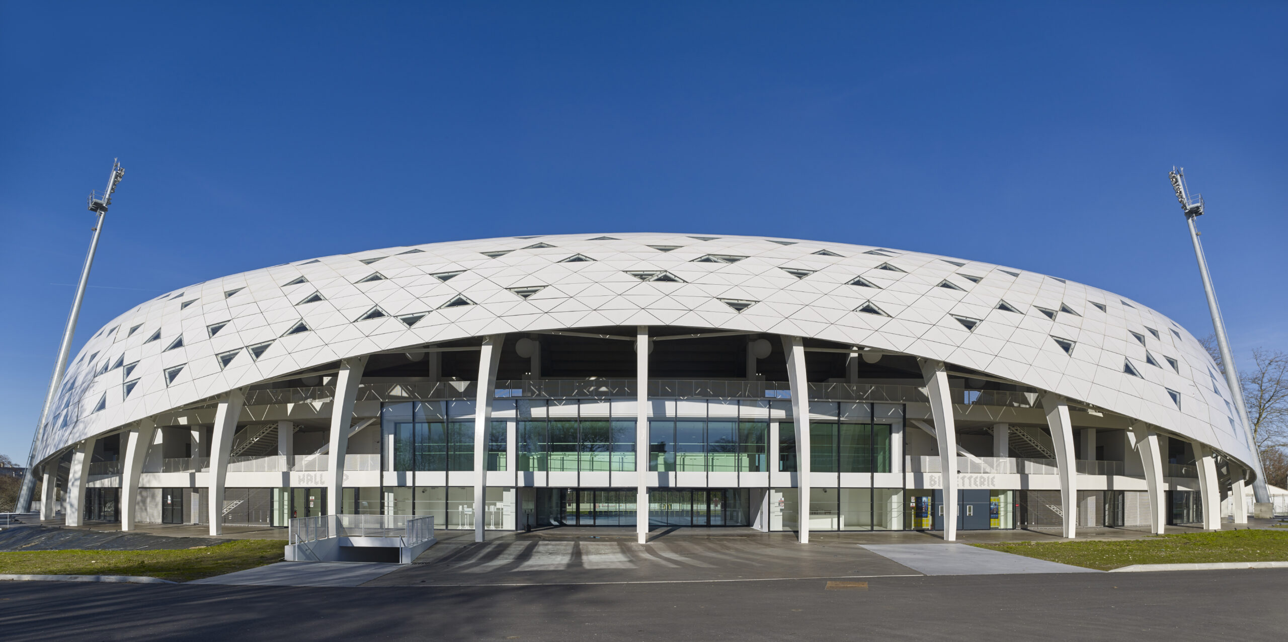 Entrée principale du stade avec vue sur la façade sud et le restaurant du stade / Atelier Ferret Architectures