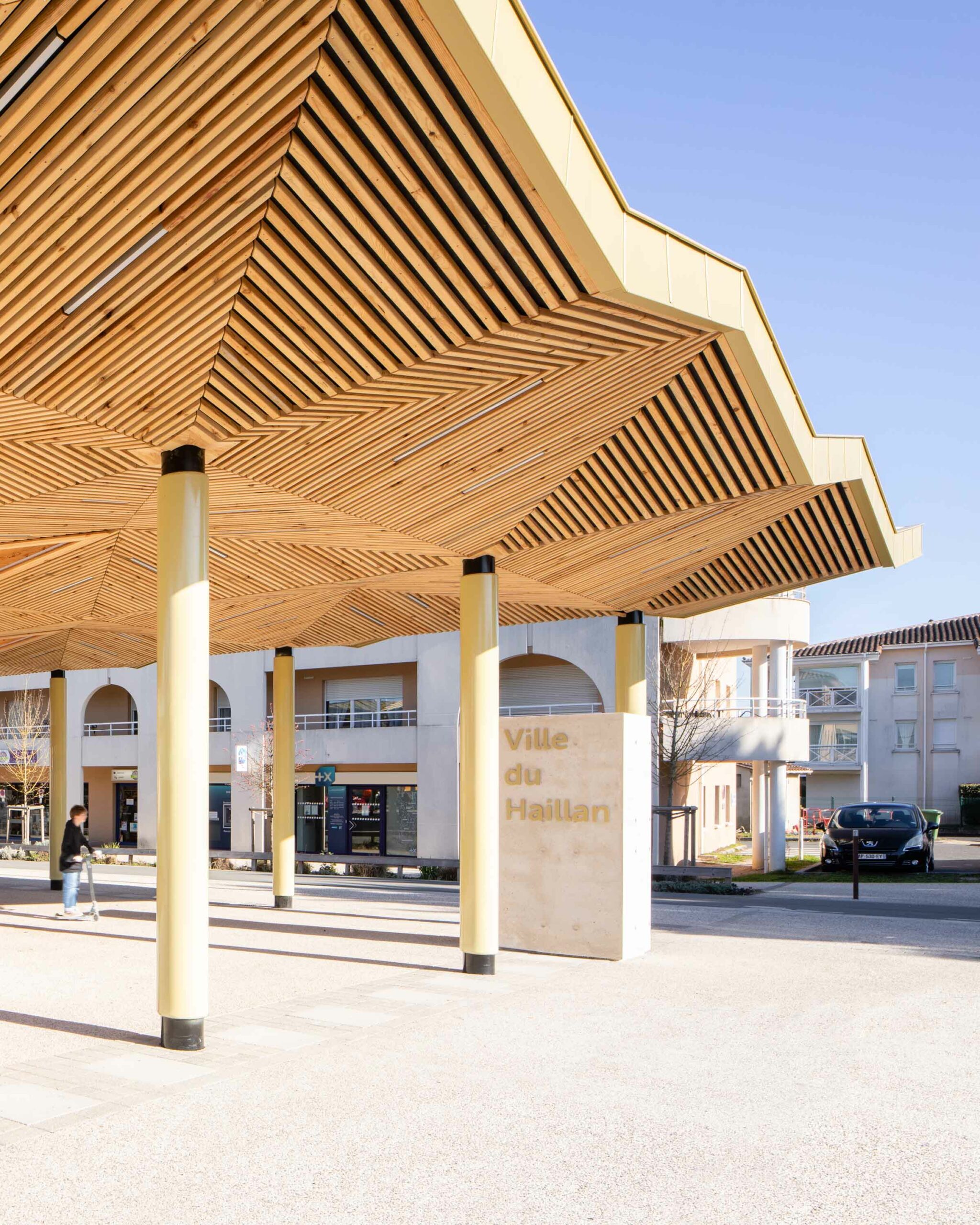 Zoom sur le bloc en béton gris comprenant la signalétique dorée de la halle / Florence VESVAL